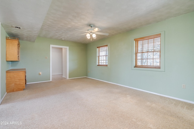 unfurnished living room featuring ceiling fan and light carpet