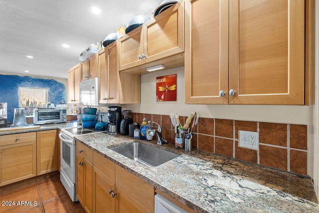 kitchen featuring light stone counters, sink, white appliances, and dark tile patterned floors