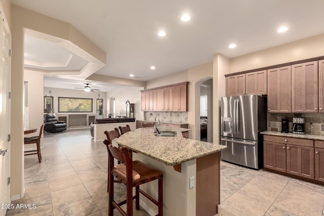 4615 S Primrose Dr, Gold Canyon, AZ 85118 - kitchen with stainless steel fridge, a sink, a breakfast bar area, arched walkways, and tasteful backsplash
