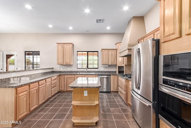 kitchen with sink, appliances with stainless steel finishes, a kitchen island, kitchen peninsula, and light brown cabinets