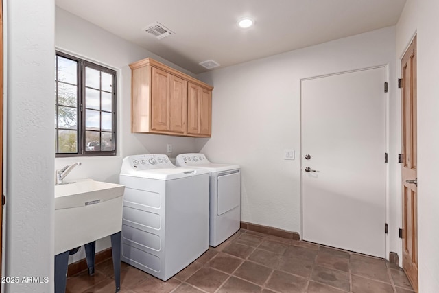 clothes washing area with separate washer and dryer and cabinets