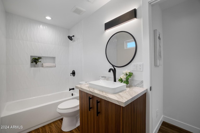 full bathroom with vanity, tiled shower / bath combo, wood-type flooring, and toilet