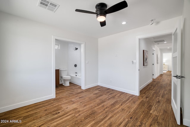 unfurnished bedroom with ensuite bathroom, dark wood-type flooring, and ceiling fan