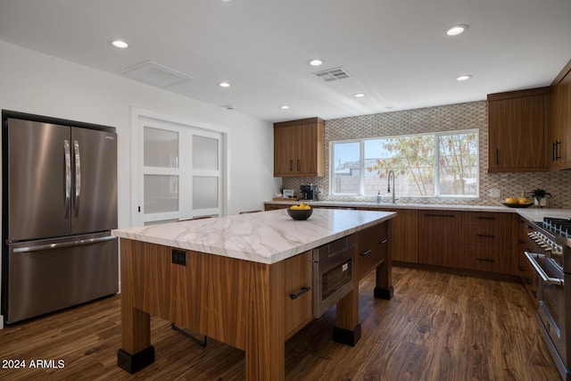 kitchen featuring stainless steel fridge, dark wood-type flooring, a center island, light stone counters, and decorative backsplash