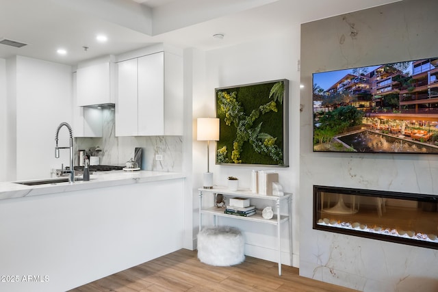 kitchen featuring backsplash, sink, white cabinets, and light wood-type flooring