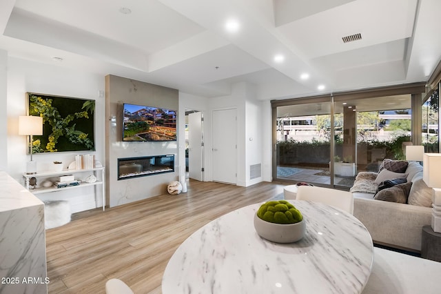 living room with light hardwood / wood-style floors and a tray ceiling