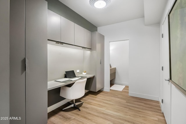 office with built in desk and light hardwood / wood-style flooring