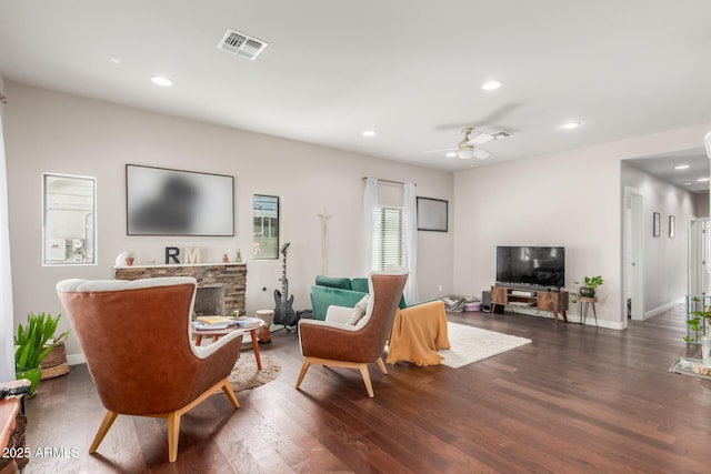 living area with visible vents, a ceiling fan, wood finished floors, recessed lighting, and a stone fireplace