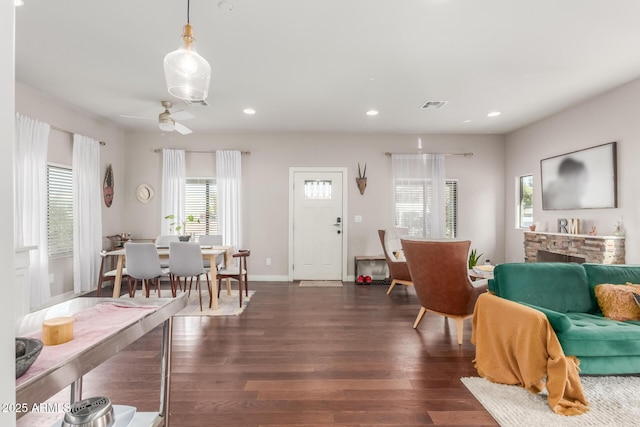 living area with recessed lighting, visible vents, a stone fireplace, and wood finished floors