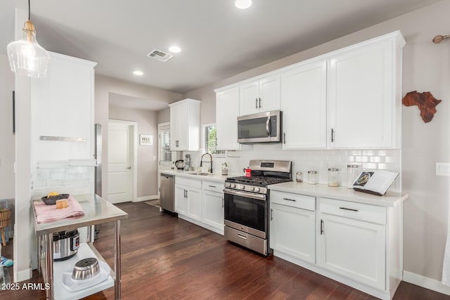 kitchen with visible vents, dark wood-type flooring, a sink, tasteful backsplash, and stainless steel appliances