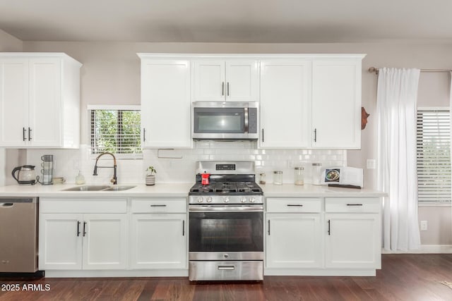 kitchen featuring tasteful backsplash, light countertops, appliances with stainless steel finishes, white cabinetry, and a sink