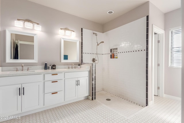 bathroom with a sink, double vanity, and a tile shower