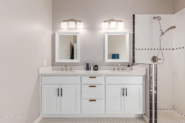 bathroom with double vanity, tiled shower, and a sink