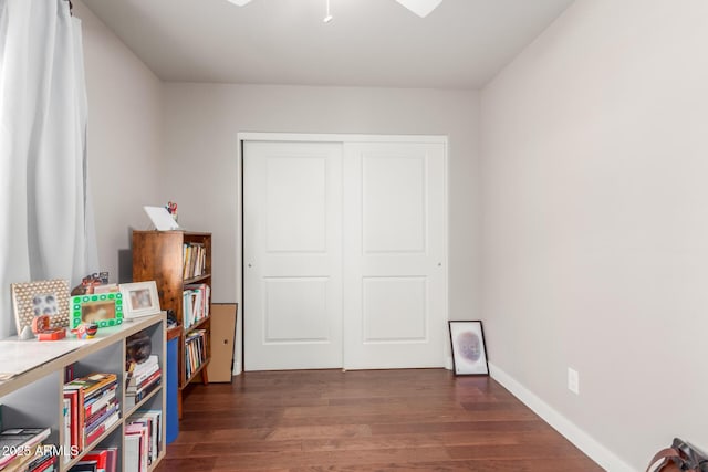 bedroom with baseboards, dark wood-style flooring, and a closet