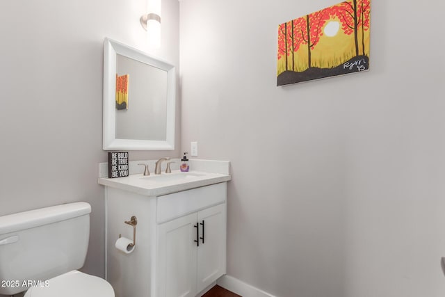 bathroom featuring toilet, vanity, and baseboards