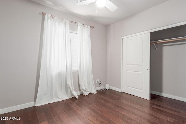 unfurnished bedroom featuring a closet, ceiling fan, dark wood-type flooring, and baseboards