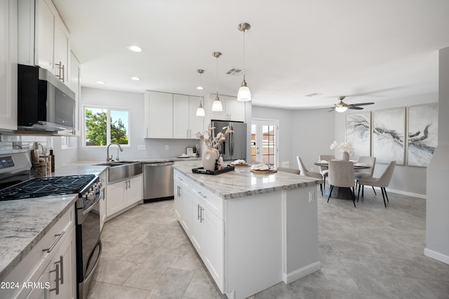 kitchen with ceiling fan, a center island, pendant lighting, white cabinets, and appliances with stainless steel finishes