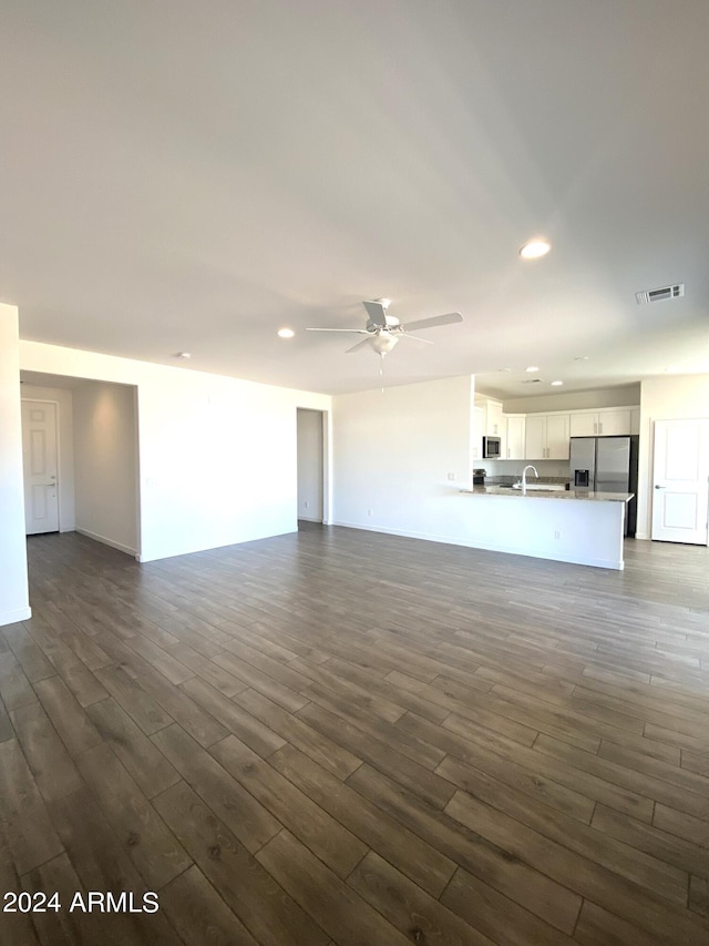 unfurnished living room with ceiling fan, sink, and dark hardwood / wood-style flooring