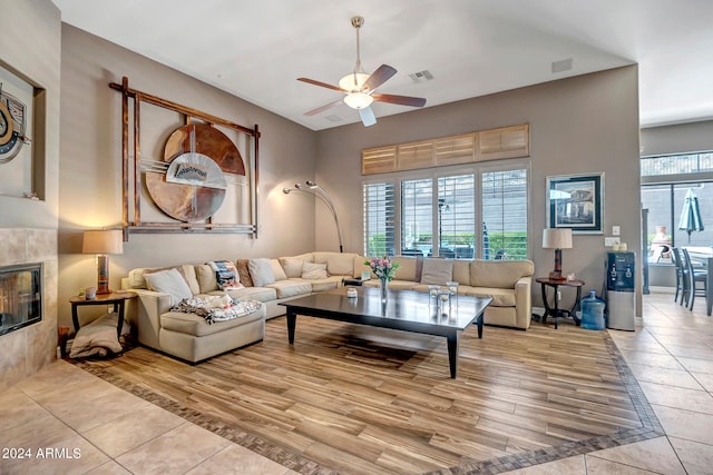 living room featuring ceiling fan, a fireplace, and light hardwood / wood-style floors