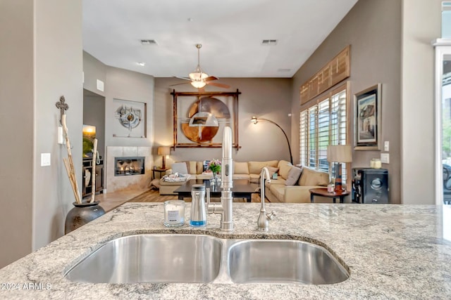 kitchen with a fireplace, a sink, visible vents, and light stone countertops