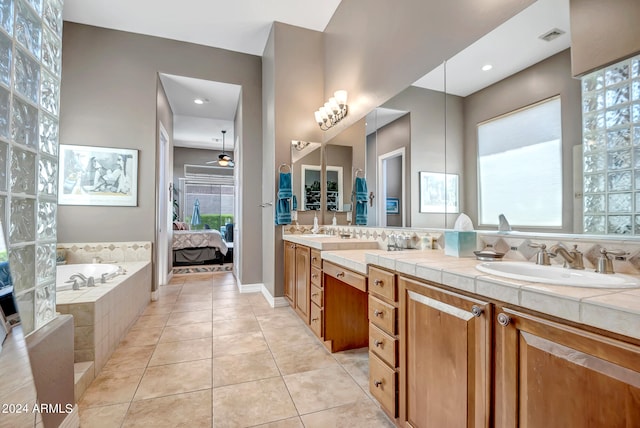 bathroom with tile patterned flooring, vanity, tiled bath, and ceiling fan