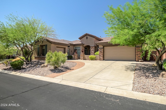 mediterranean / spanish house featuring a garage, concrete driveway, stone siding, a tiled roof, and stucco siding