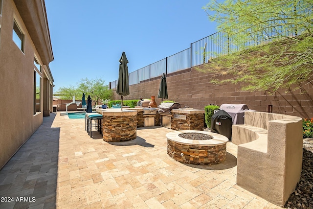 view of patio / terrace with outdoor dry bar, an outdoor kitchen, area for grilling, a fenced backyard, and a fire pit