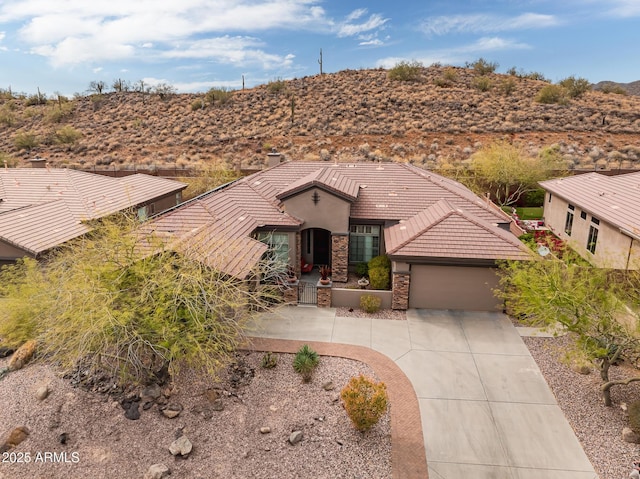 view of front of property with a tile roof, stucco siding, an attached garage, stone siding, and driveway