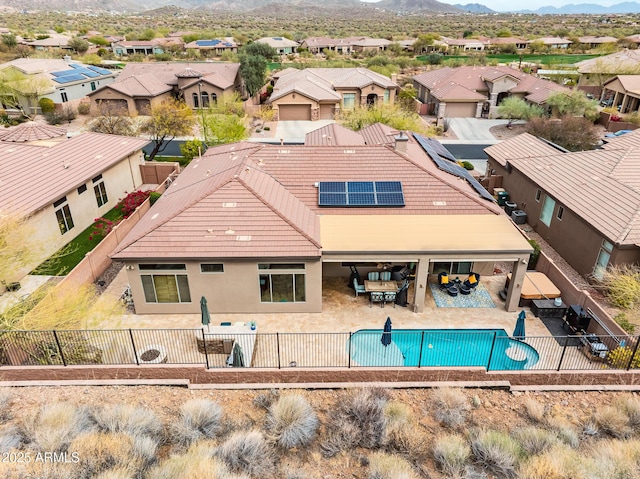 back of property featuring solar panels, a patio area, a fenced backyard, and a residential view