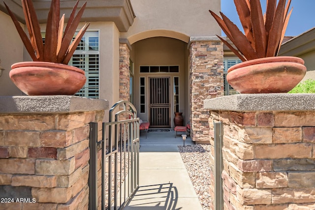 view of exterior entry with stone siding and a gate