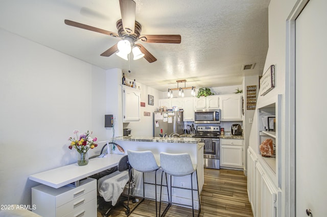 2301 E University Dr Unit 488, Mesa, AZ 85213 - kitchen featuring appliances with stainless steel finishes, white cabinetry, a peninsula, a breakfast bar, and a ceiling fan