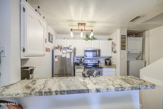 2301 E University Dr Unit 488, Mesa, AZ 85213 - kitchen with stainless steel appliances, stacked washer and clothes dryer, white cabinets, a peninsula, and a textured ceiling