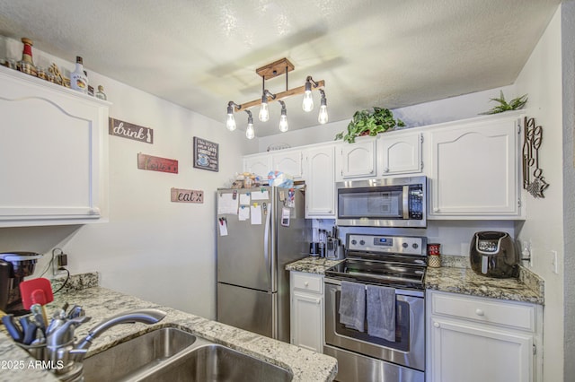 2301 E University Dr Unit 488, Mesa, AZ 85213 - kitchen featuring stainless steel appliances, white cabinets, a sink, light stone countertops, and a textured ceiling