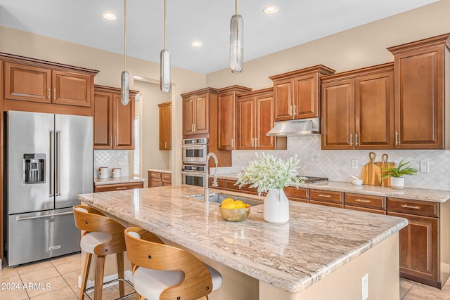 kitchen with stainless steel appliances, pendant lighting, tasteful backsplash, and an island with sink