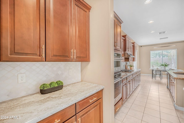 kitchen with light stone counters, light tile patterned floors, visible vents, stainless steel appliances, and decorative backsplash