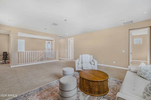 sitting room with an upstairs landing, visible vents, baseboards, and carpet floors