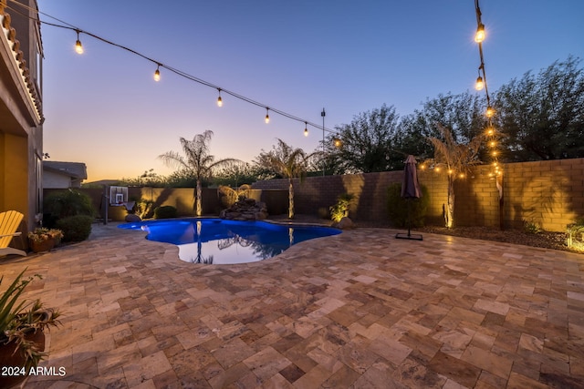 pool at dusk featuring a patio area, a fenced in pool, and a fenced backyard