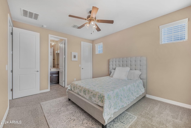 carpeted bedroom featuring visible vents, a ceiling fan, ensuite bathroom, and baseboards