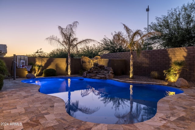 pool at dusk featuring a patio area, a fenced in pool, and a fenced backyard