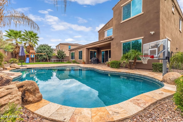 view of pool featuring fence, a playground, grilling area, a fenced in pool, and a patio area