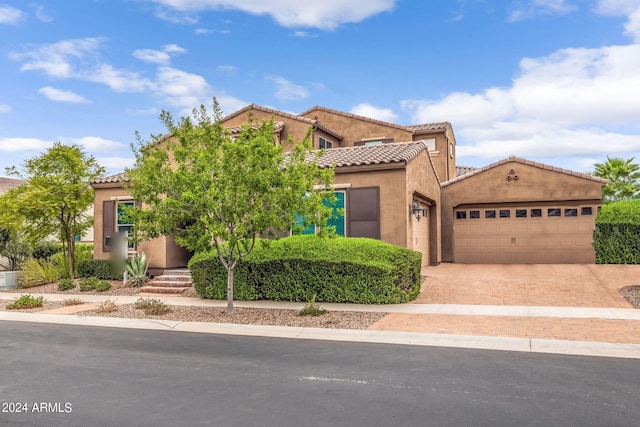 mediterranean / spanish-style home with stucco siding, driveway, an attached garage, and a tiled roof