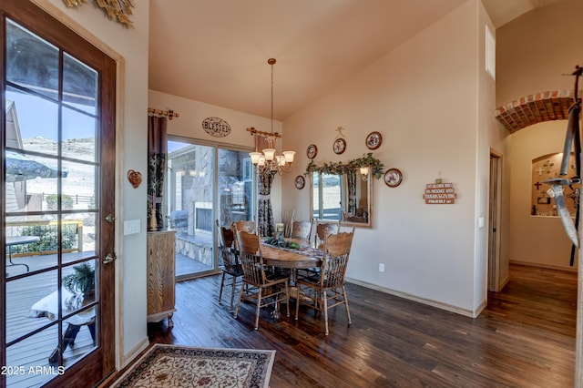 dining space with high vaulted ceiling, a notable chandelier, dark wood-style floors, and baseboards