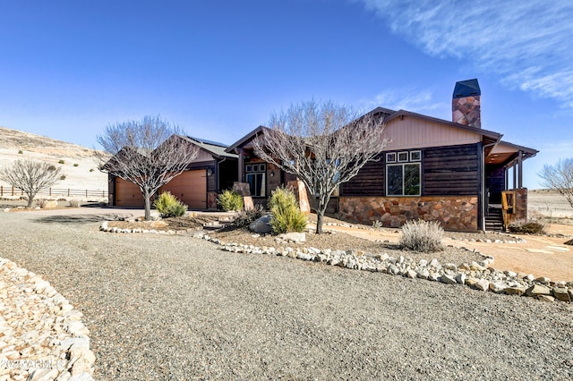 ranch-style house featuring driveway, stone siding, a chimney, fence, and a garage