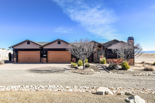 view of front of property with a chimney, stone siding, a garage, and concrete driveway