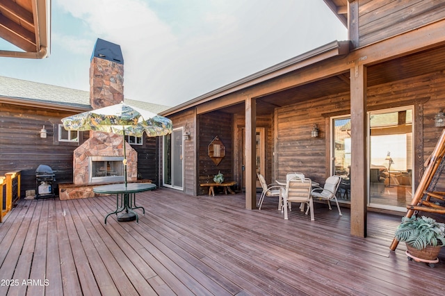 wooden deck with grilling area, outdoor dining area, and an outdoor stone fireplace