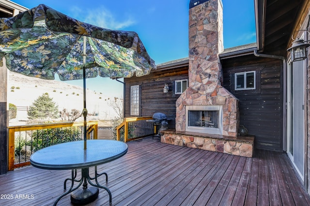 deck with an outdoor stone fireplace and grilling area
