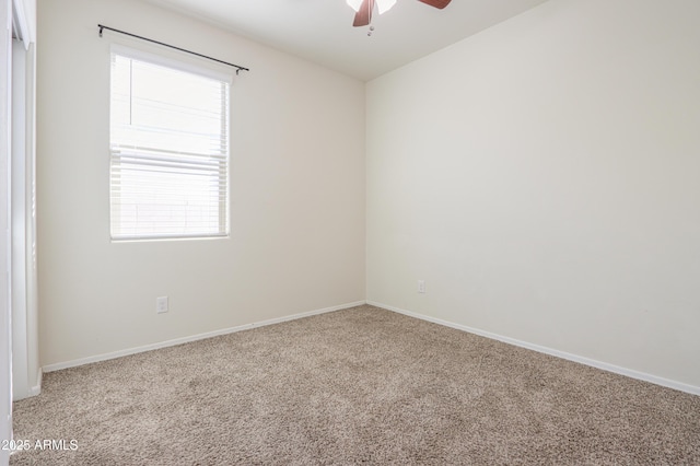 carpeted spare room featuring a ceiling fan and baseboards