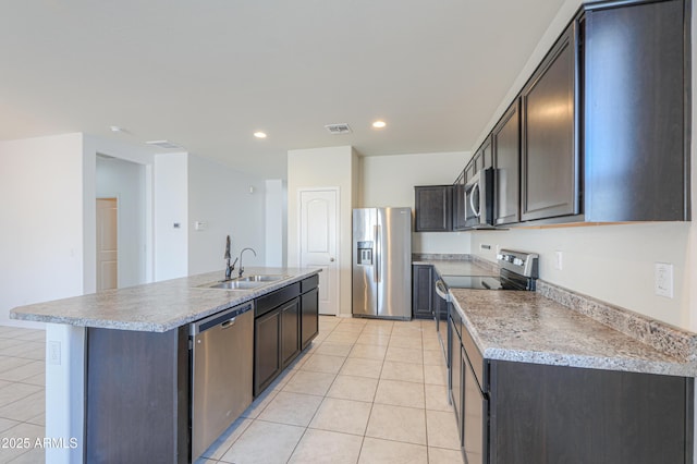 kitchen with light tile patterned floors, a kitchen island with sink, stainless steel appliances, a sink, and visible vents