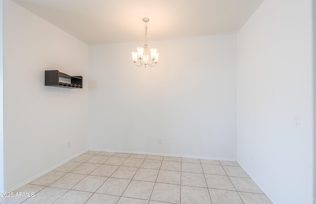 unfurnished room featuring baseboards and an inviting chandelier