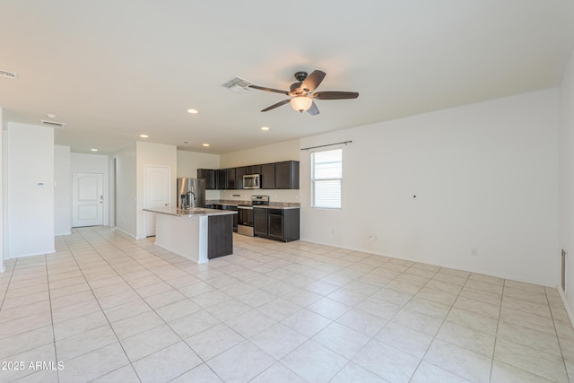 kitchen with appliances with stainless steel finishes, open floor plan, visible vents, and an island with sink